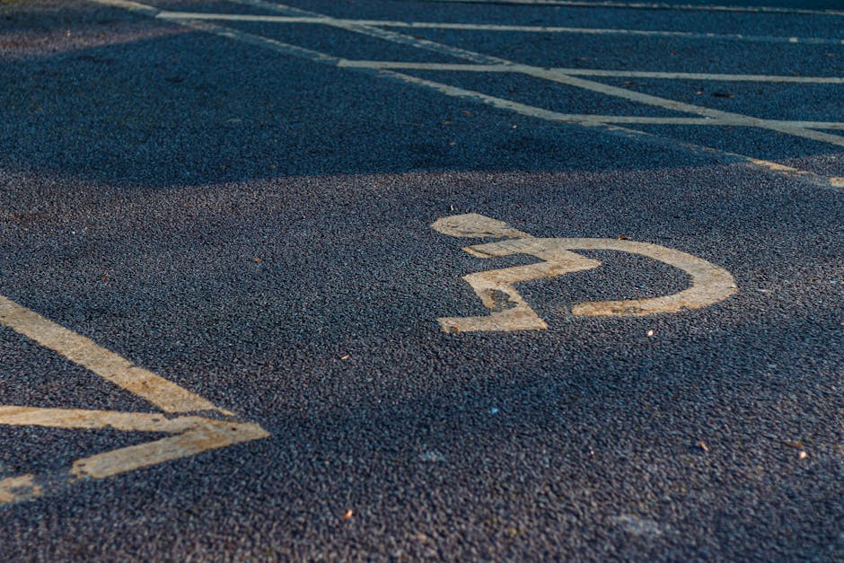 Close-up view of a designated parking space on an asphalt surface during the daytime, marked with a white number '22' painted on the ground, with surrounding diagonal white lines indicating a parking bay. The asphalt has a rough texture, and the paint shows slight signs of wear. In the background, part of a vehicle is visible, with a focus on parking area markings. This scene is relevant to house removals and furniture transport activities, illustrating parking arrangements and access points that are critical for efficient home relocation and loading processes. The image reflects aspects of moving logistics, such as parking allocation and space planning, which Man with Van New Cross manages during residential moves, specifically in the context of packing and loading their vehicles.